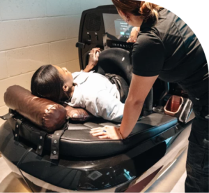 Woman lying in the INFRASLIMX weight loss therapy machine with LED monitor displaying performance metrics