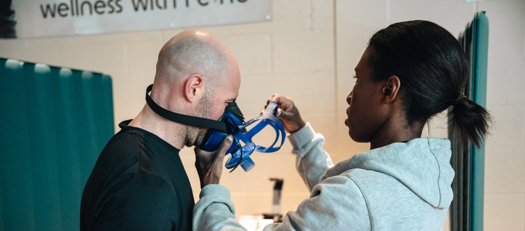 Wellness specialist assisting client with breathing equipment during a biohacking treatment at Re:nu London