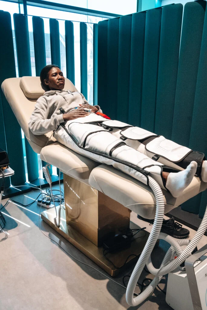 Woman lying on a treatment bed wearing Stendo compression device on her lower body