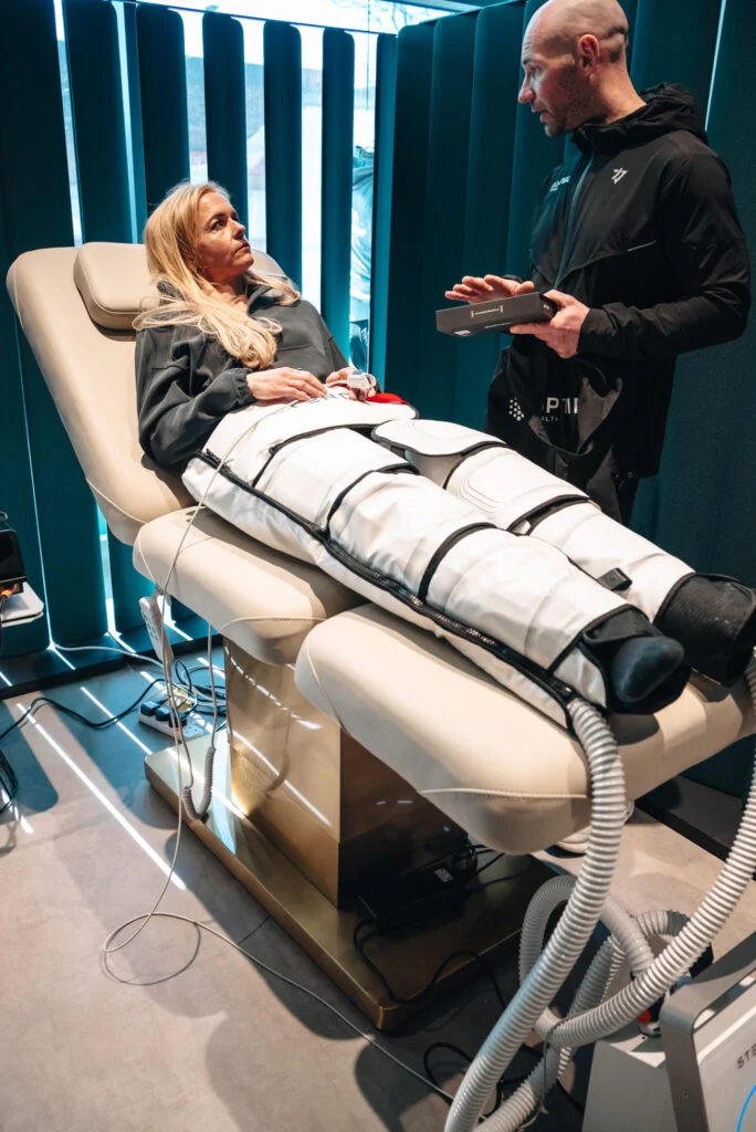 Woman relaxed in a lower body compression device discussing the treatment with a Re:nu wellness consultant.