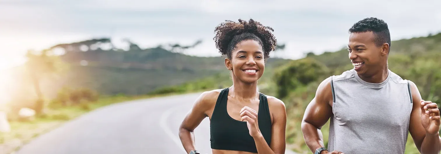 Two smiling people jogging along a road and smiling