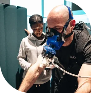 Re:nu wellness consultant monitoring a client undergoing PNOE breath analysis wearing a specialist breathing mask.