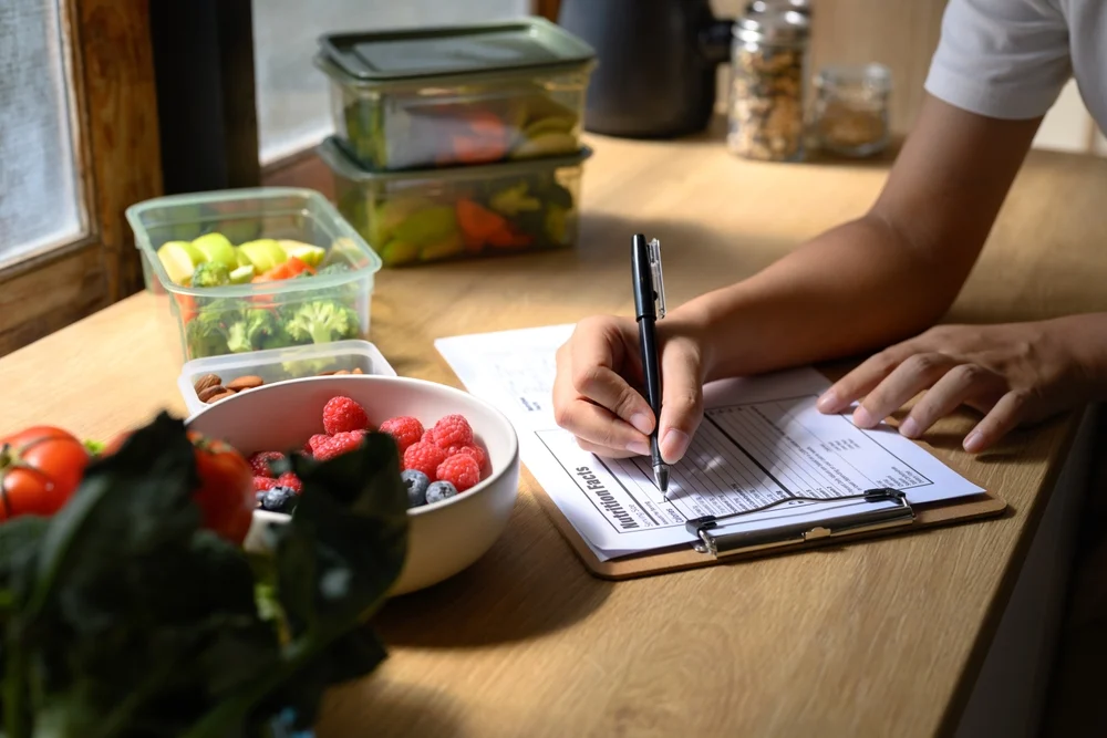 Nutritionist,writing,meal,plan,and,nutrition,facts,on,a,clipboard